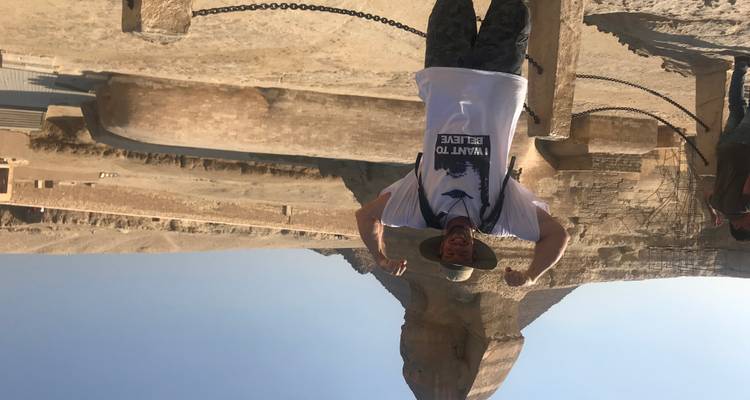 Persoon die poseert voor een groot oud standbeeld.