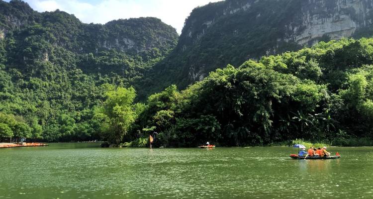 Botes en un río sereno rodeado de colinas verdes exuberantes.