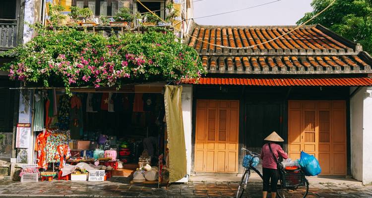 Colorful shop front with flowers and a person with a bicycle.