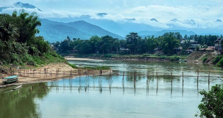 Rivière aux rives verdoyantes avec des montagnes au loin.