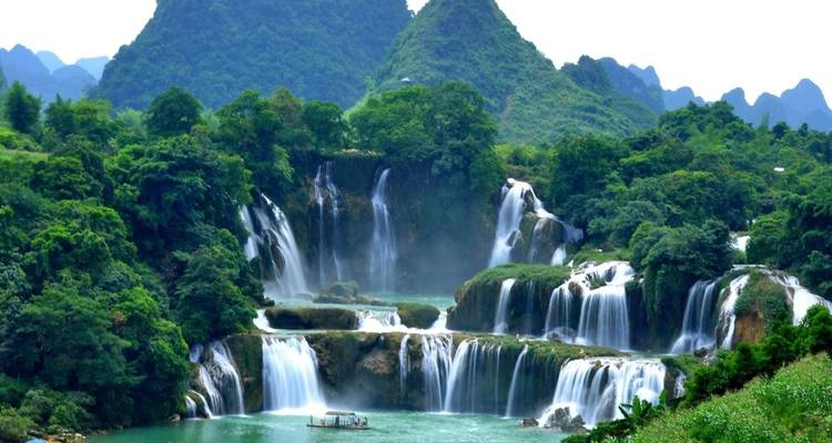 Une magnifique cascade entourée de collines vertes.
