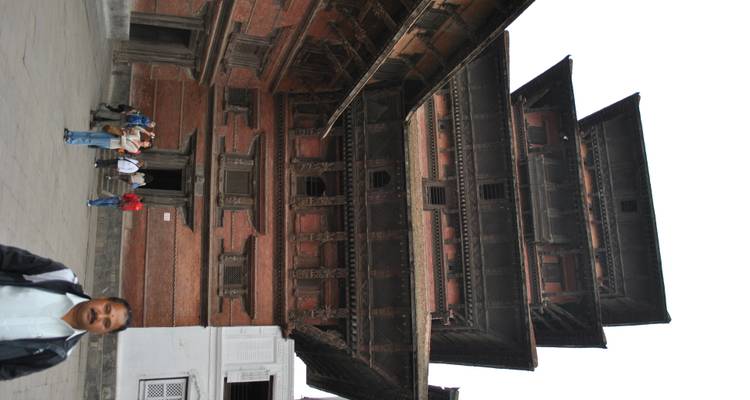 Tall multi-tiered pagoda palace built of red brick and timber, visitors gathered at its entrance