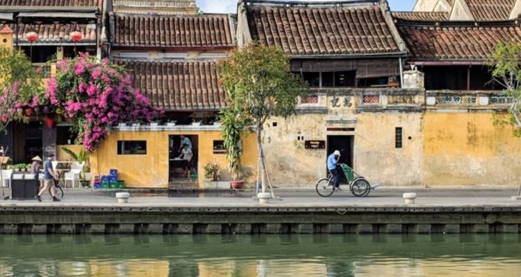 Ciclista en una calle junto a un canal con edificios históricos.