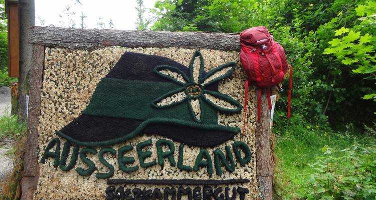 Gravure d'enseigne sur bois avec un sac à dos rouge suspendu à côté.