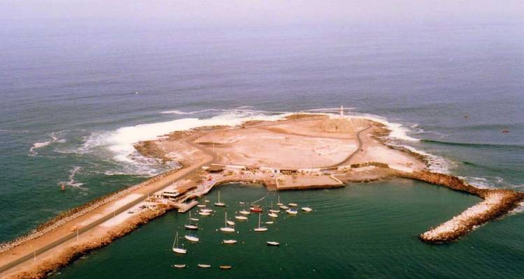 Eine Insel, die durch einen schmalen Damm verbunden ist, mit Booten im Hafen.