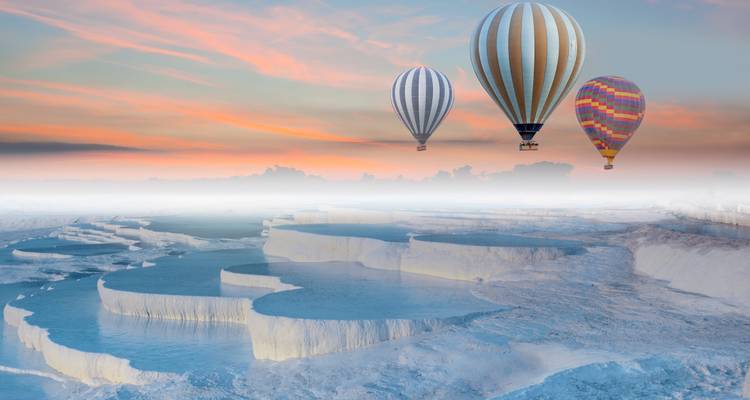 Globos de aire caliente sobre terrazas de travertino al atardecer.