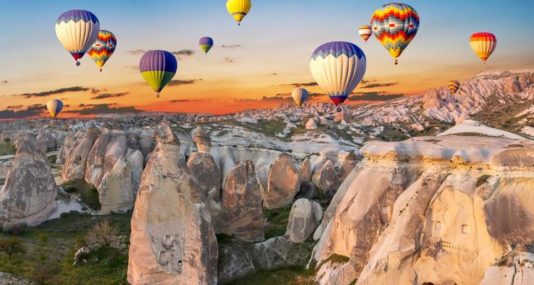 Globos aerostáticos sobre las formaciones rocosas de Capadocia al atardecer.