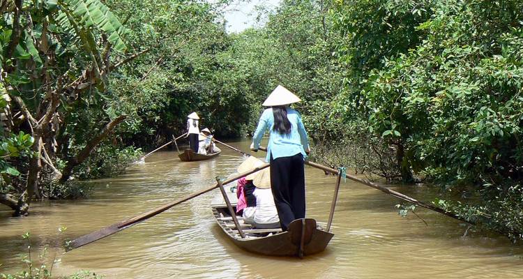 Mensen die kleine bootjes peddelen op een rivier omringd door dichte bomen.