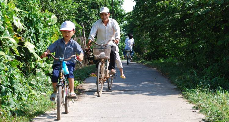 Familie die op fietsen rijdt op een pad omzoomd met groen.
