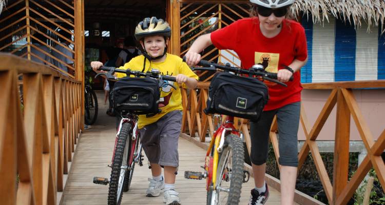 Kinderen met fietsen op een houten brug.