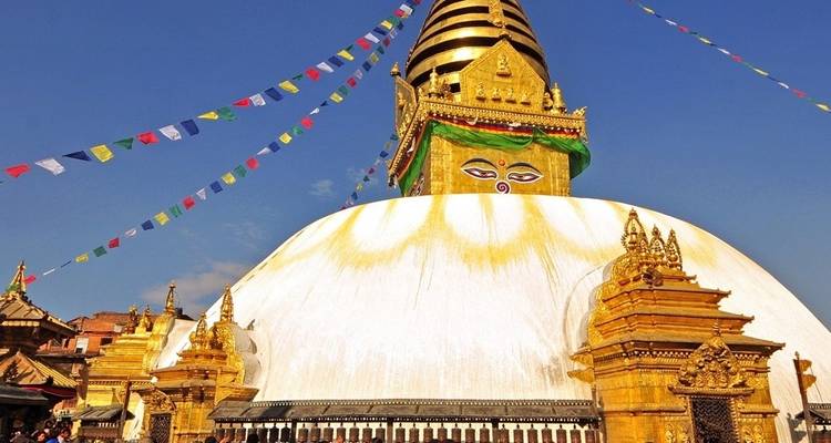 Swayambhunath Stupa geschmückt mit Gebetsfahnen unter blauem Himmel.