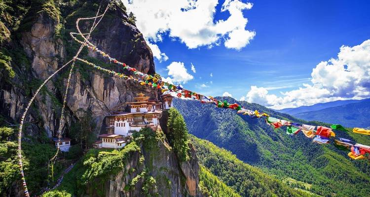 Monasterio del Nido del Tigre encaramado en un acantilado con banderas de oración.