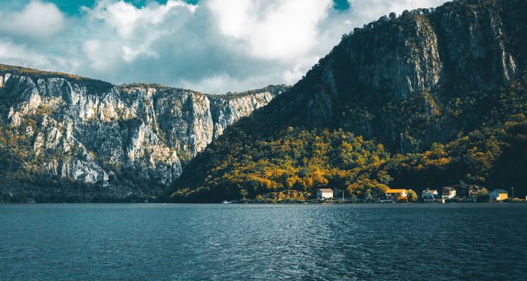 Lac de montagne avec des falaises et quelques habitations près du rivage.