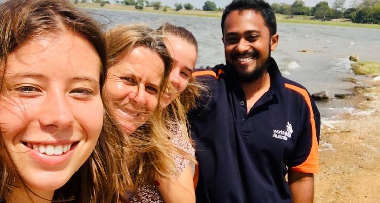 Group of smiling people at a lakeside.