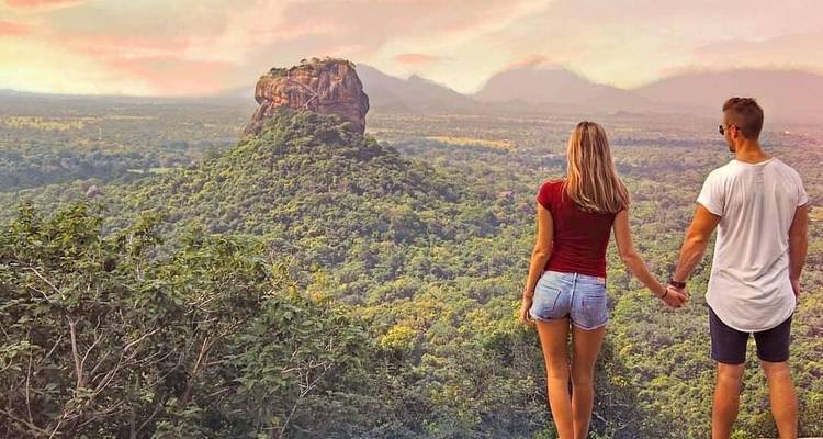 Couple holding hands overlooking a scenic landscape with Sigiriya rock.