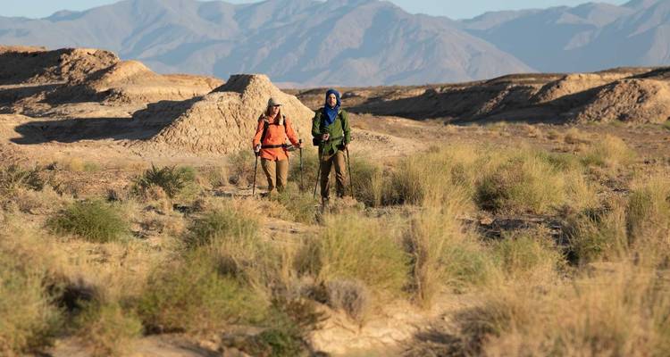 Twee mensen die door een woestijnlandschap lopen.