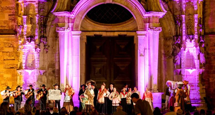 Spectacle nocturne de musique et de danse portugaises traditionnelles sur une scène façade d'église illuminée.