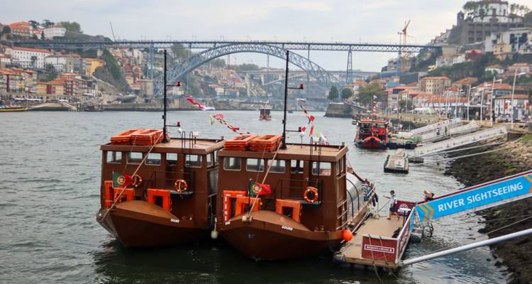 Deux bateaux traditionnels amarrés sur le Douro avec le pont Dom Luís I de Porto en arrière-plan.