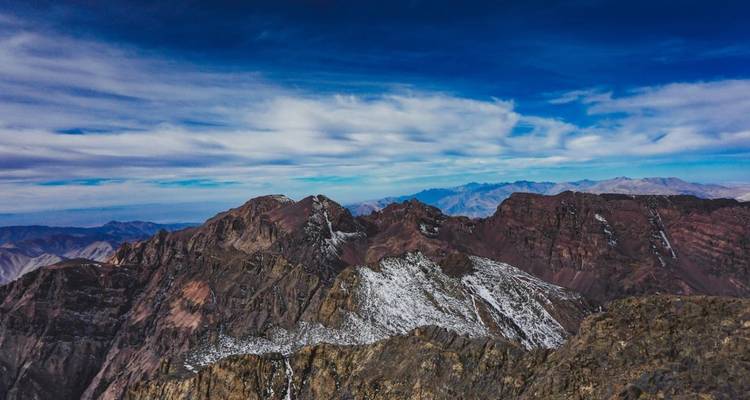 Rocky mountain peaks with patches of snow under a deep blue sky.
