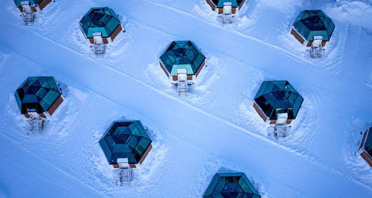 Vue aérienne de cabanes en verre en forme d'igloo sur la neige.
