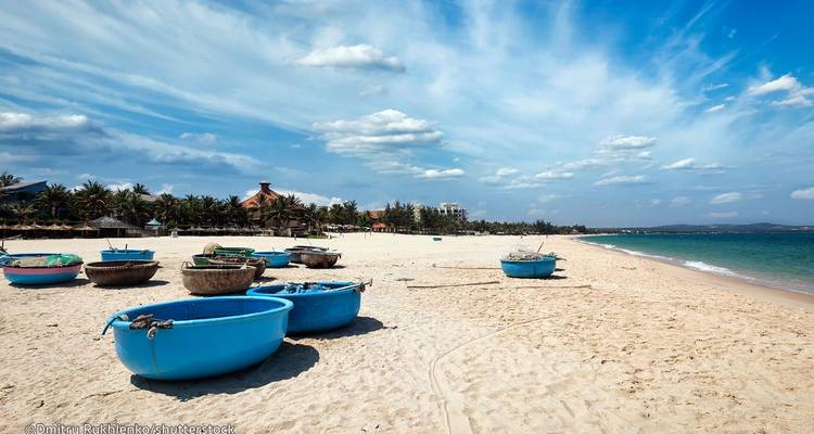 Playa vacía con botes azules redondos en la arena.