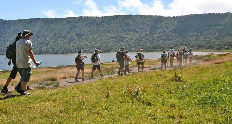 Gruppe von Touristen, die in der Nähe eines Sees in der Savanne spazieren gehen.