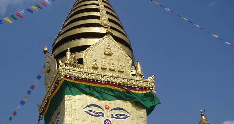 Golden stupa top with intricate designs and blue sky background.