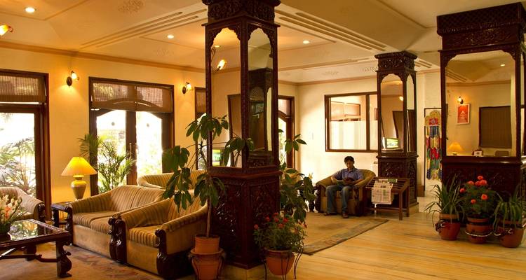 Hotellobby met banken, decoratieve zuilen en kamerplanten.