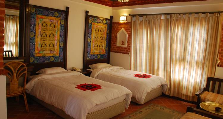 Hotelkamer met twee eenpersoonsbedden, bakstenen muren en decoratieve stoffen.