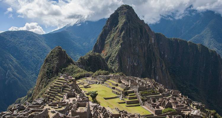 Vista panorámica clásica de las ruinas de Machu Picchu con el imponente pico Huayna Picchu y las montañas andinas de fondo.