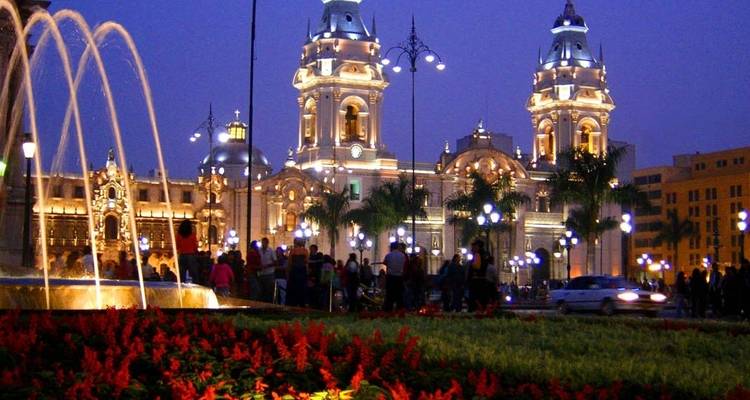 Verlichte kathedraal in de nacht met een fontein op de voorgrond.
