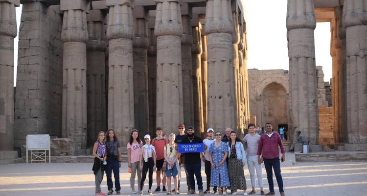 Un groupe de touristes posant devant des colonnes antiques.