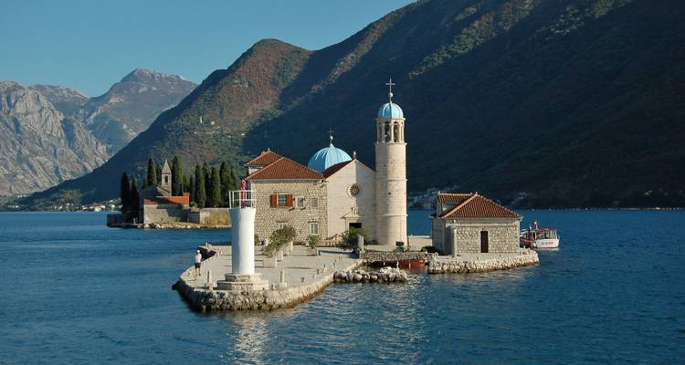 Island with church buildings, surrounded by water and rugged mountains.