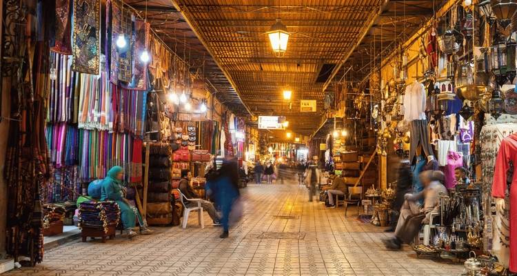 Ein lebendiger Souk mit verschiedenen ausgestellten Waren und sich bewegenden Menschen.