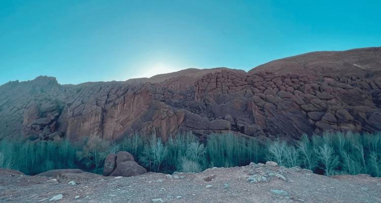Raue Canyonlandschaft mit Bäumen und Feldern im Tal.