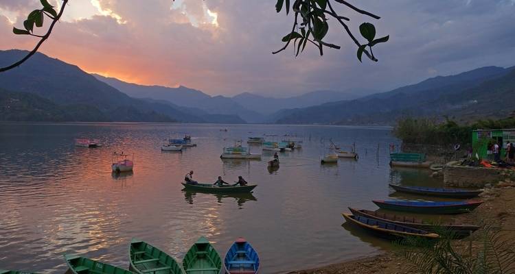 Boote auf einem See mit Bergen bei Sonnenuntergang.
