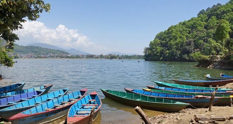 See mit bunten Booten und grünen Bergen.
