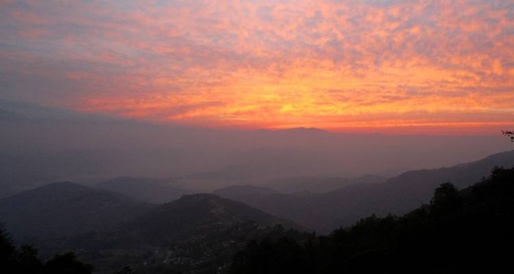Sonnenuntergang über neblige Berglandschaft.