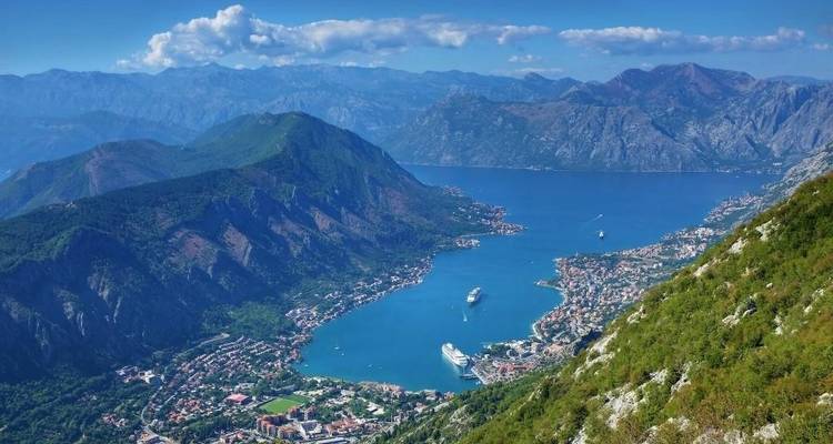 Aerial view of a coastal bay surrounded by mountains and houses.