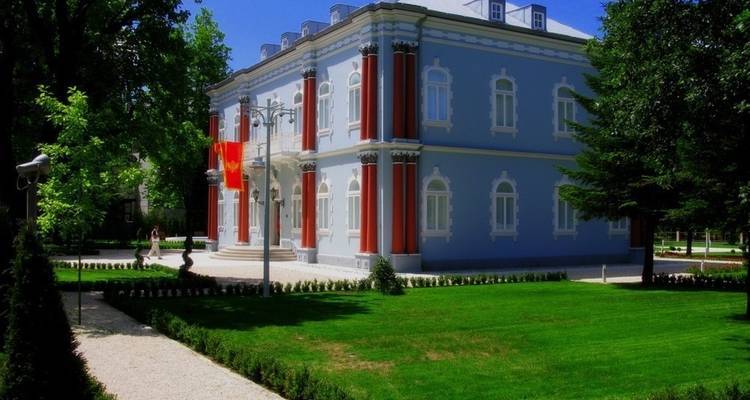 Elegant governmental building with red columns surrounded by manicured gardens.