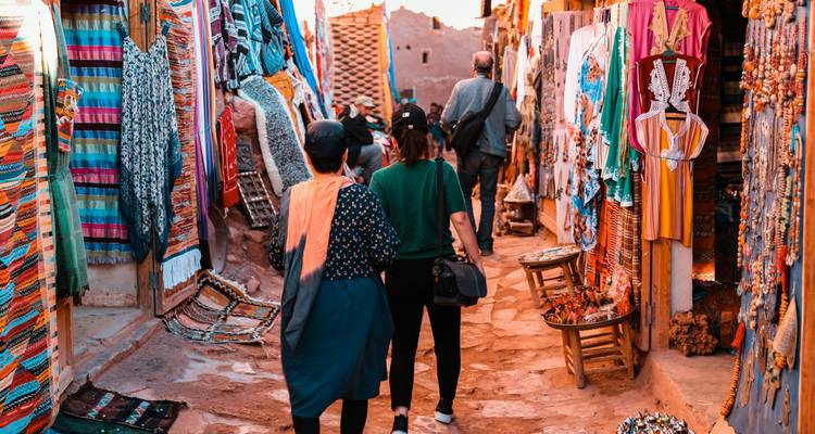 Schmale Straße mit Marktständen und Touristen.