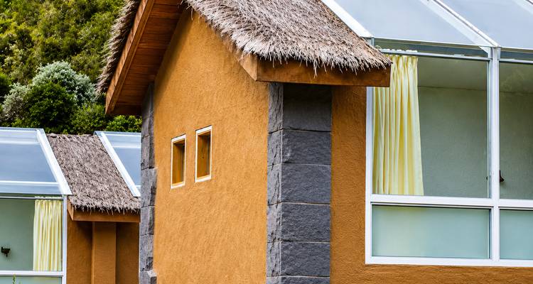 Modern rustieke lodge met rietgedekte daken en grote glazen ramen in de Andes.