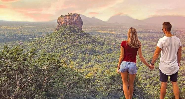 Pareja tomada de la mano contemplando la Roca de Sigiriya durante el atardecer.