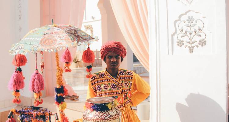 Persoon in traditionele kleding bij kleurrijke decoraties.