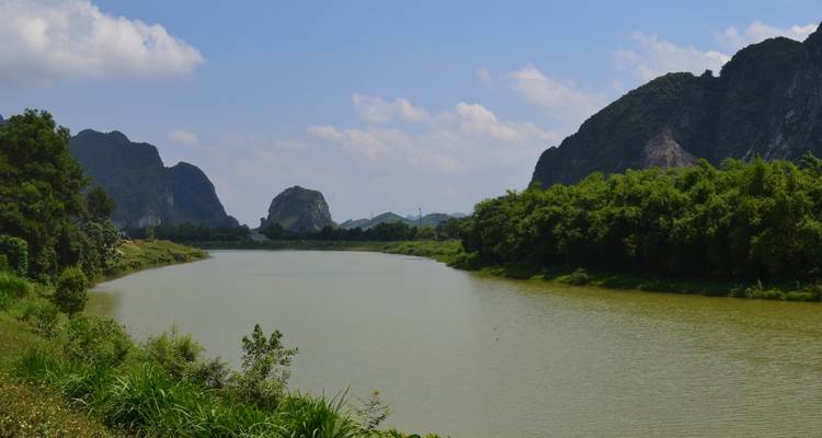 Ruhiger Fluss, der sich durch ein üppiges Tal mit felsigen Bergen schlängelt.