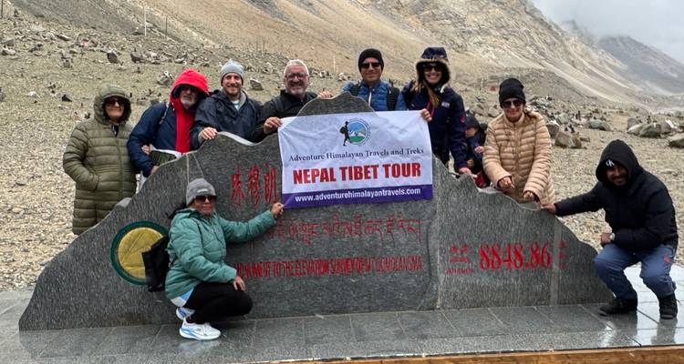 Groupe de personnes posant derrière un panneau de voyage Népal Tibet.