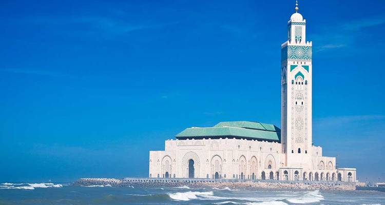 Escena costera con una mezquita y olas rompiendo en la orilla.