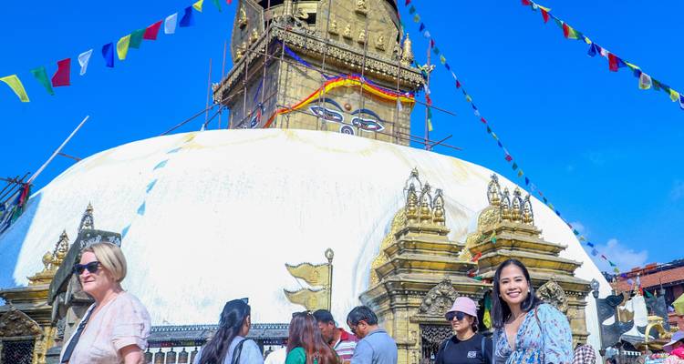 Stupa avec drapeaux de prière et personnes autour.