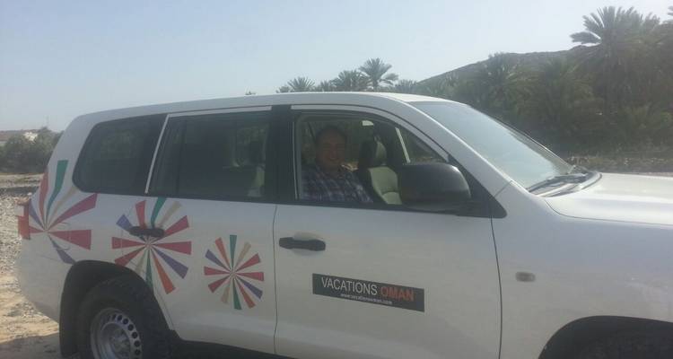 Vehículo con un logotipo de una empresa de vacaciones estacionado junto a palmeras.