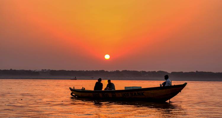 Silhouetted boat on a river at sunset.